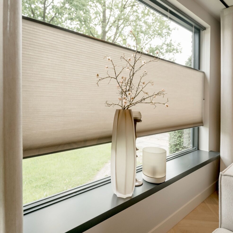 Detailbild eines Fensters mit Sonnenschutz von JOKA in Form eines hellen Plissees.