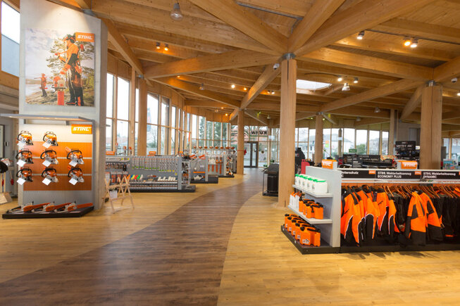 JOKA-Referenzen-Designboden-Raumbild-Ladenbau Raumbild eines dunklen Ladengeschäfts, in dem ein dunkler 555 JOKA Designboden im Pine Oak Dekor verlegt ist.