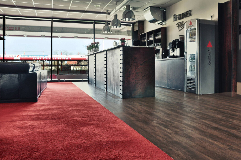 JOKA-Referenzen-Teppich-Fußballstadion-Berlin Raumbild des VIP-Bereichs im Berliner Fußballstadion, Alte Försterei. Auf dem Boden ist ein roter Hochfloor-Teppich von JOKA verlegt.