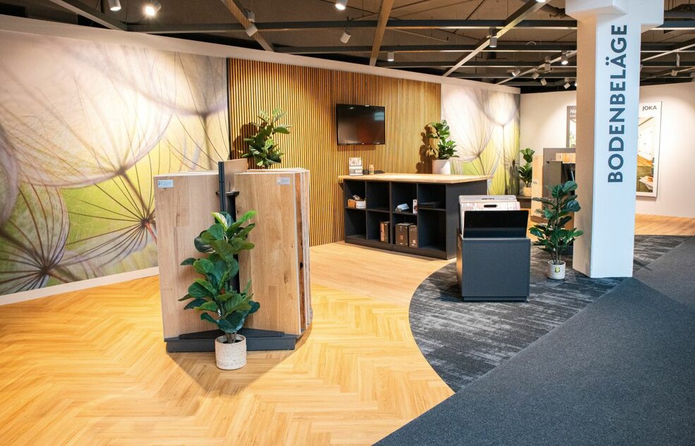 Moderne Ladenfläche im WEKO Einrichtungshaus mit JOKA Designboden in Holzoptik und wohnlicher Ausstellung.