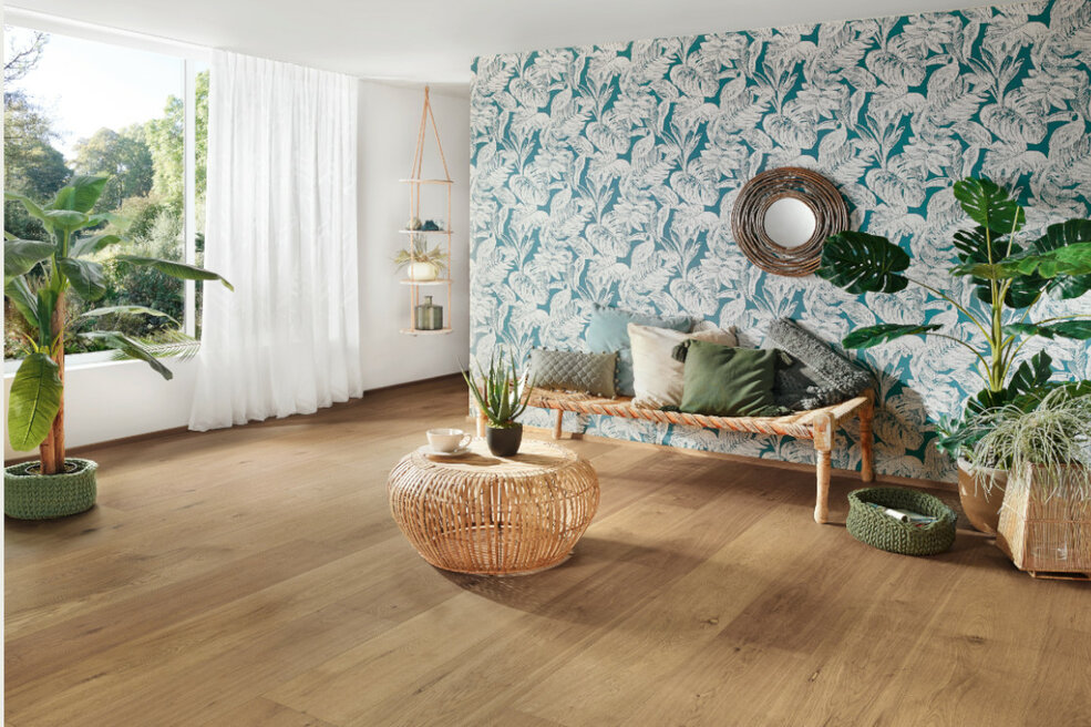 Weitläufiges Wohnzimmer mit JOKA-Bodenbelag und Palmentapete im modernen Tropical-Look.