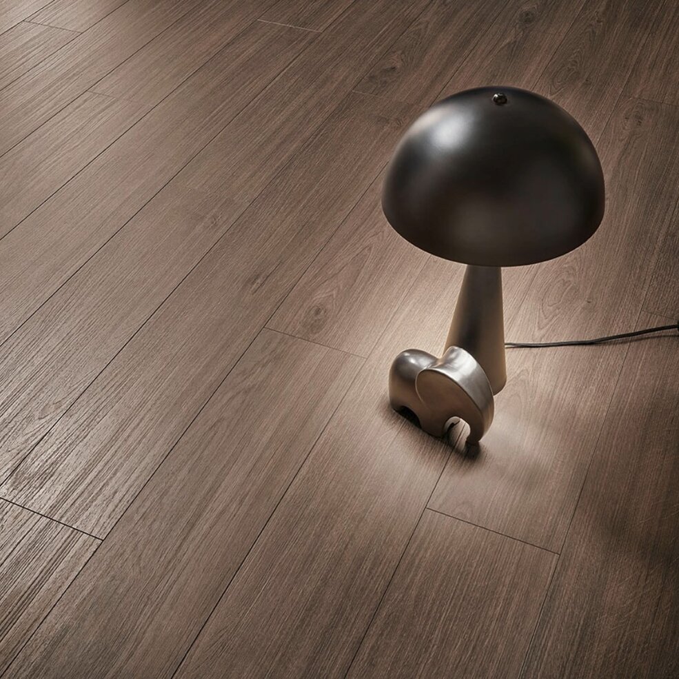 Detailbild eines dunklen, edlen Naturdesignbodens von JOKA. Darauf platziert ist eine dunkle Lampe.