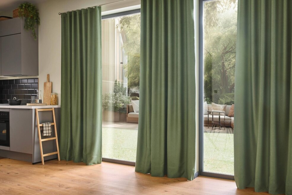 Raumbild eines Wohnzimmers mit einer breiten Fensterfront. Die angebrachten JOKA Gardinen passen zur Wohnidee Wohngenuss.