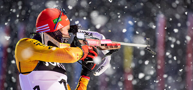 Biathlon-Athlet bei einer Schießübung in verschneiter Umgebung.