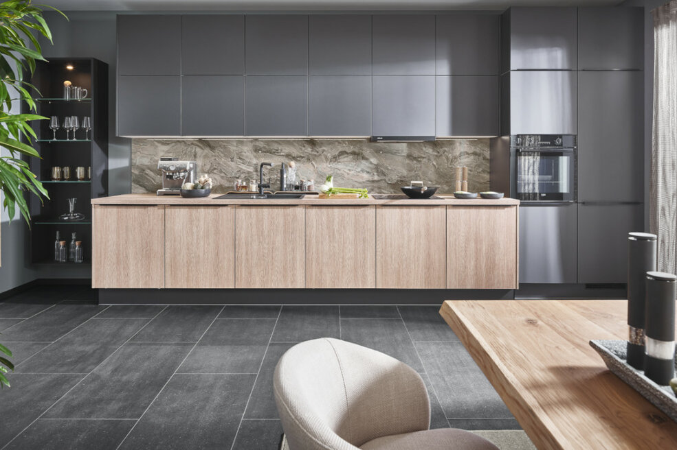 Moderne Küche in Grau und Holz mit marmorierter JOKA Rückwand.