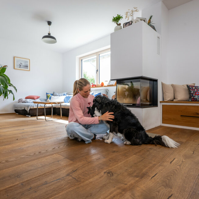 Wohnzimmer mit Kamin, JOKA Holzboden und Hund, gemütliche Wohnatmosphäre.