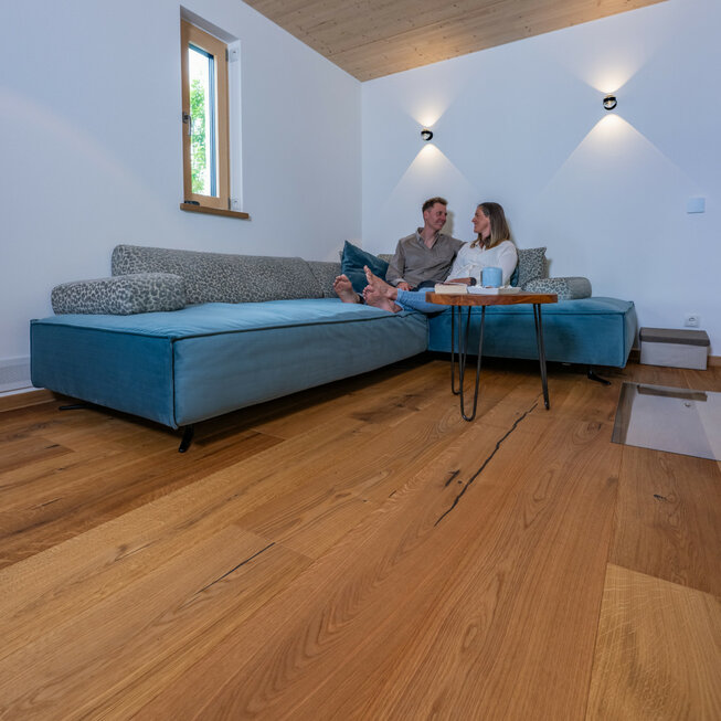 Gemütliches Wohnzimmer mit Sofa auf hellem JOKA Designboden.