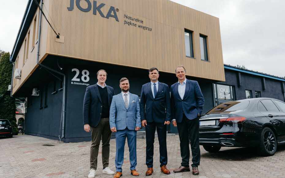 Vier Personen stehen vor dem neuen JOKA-Gebäude mit der markanten Hausnummer 11 – offizieller Start am neuen Standort.