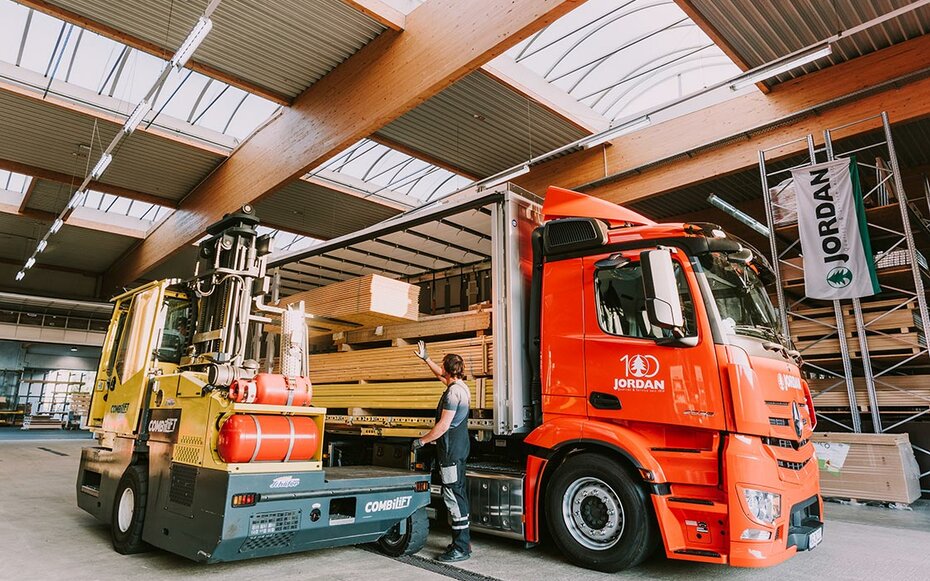 Bild eines LKWs von der Seite, der gerade durch einen Gabelstapler in einer Lagerhallebeladen wird.