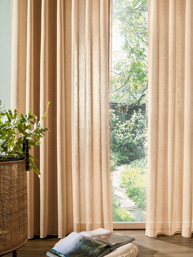 Detailaufnahme eines Fenster, das mit einer sandfarbenen Gardine verhangen ist - der optimale Sonnenschutz in der Frische Kur Wohnidee.