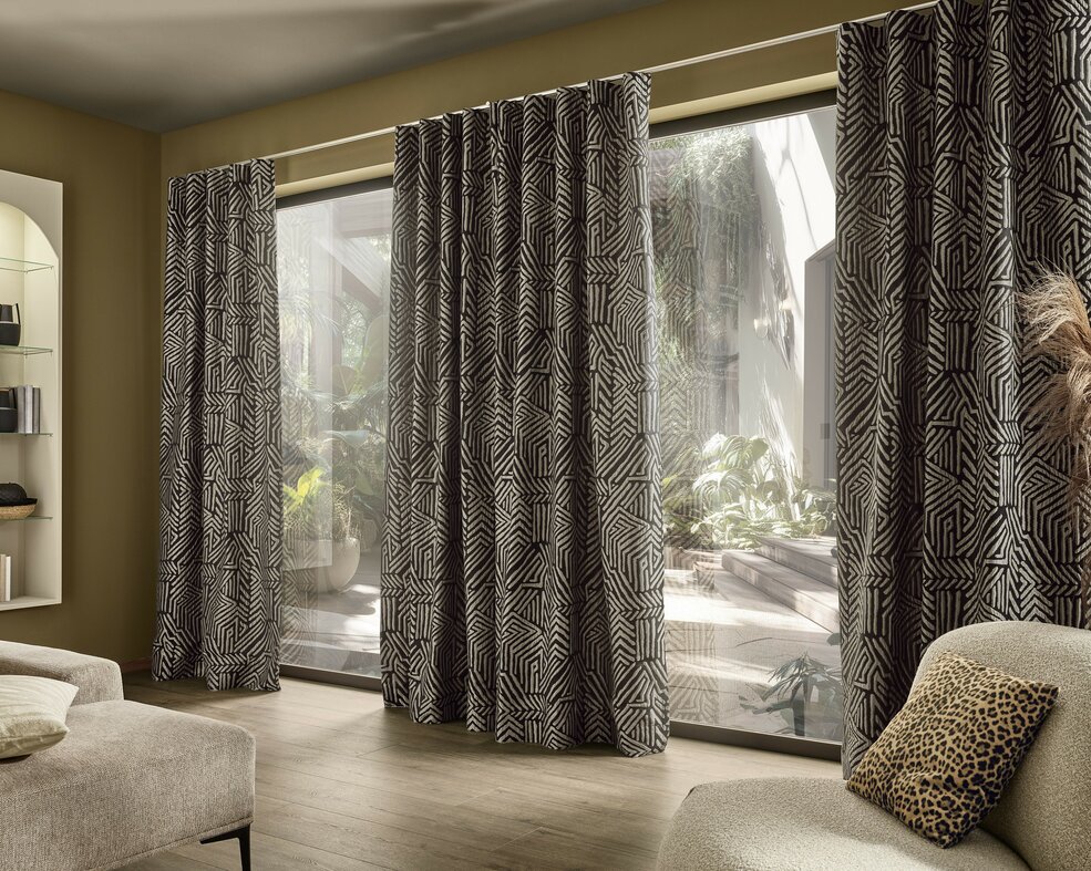 Raumbild zum Gardinenstoff KITO aus der Dekostoffkollektion Frühjahr 2026 von JOKA. Schwarz-weiß Stoff mit Muster