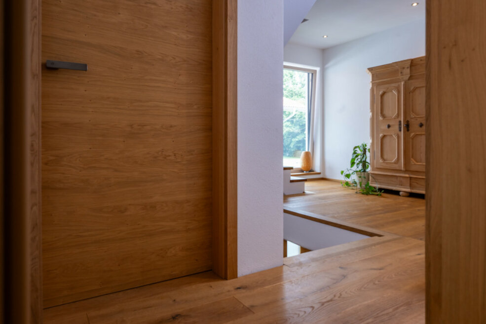 Blick durch den Flur in den Wohnbereich mit JOKA Holzboden und natürlichen Holztüren.