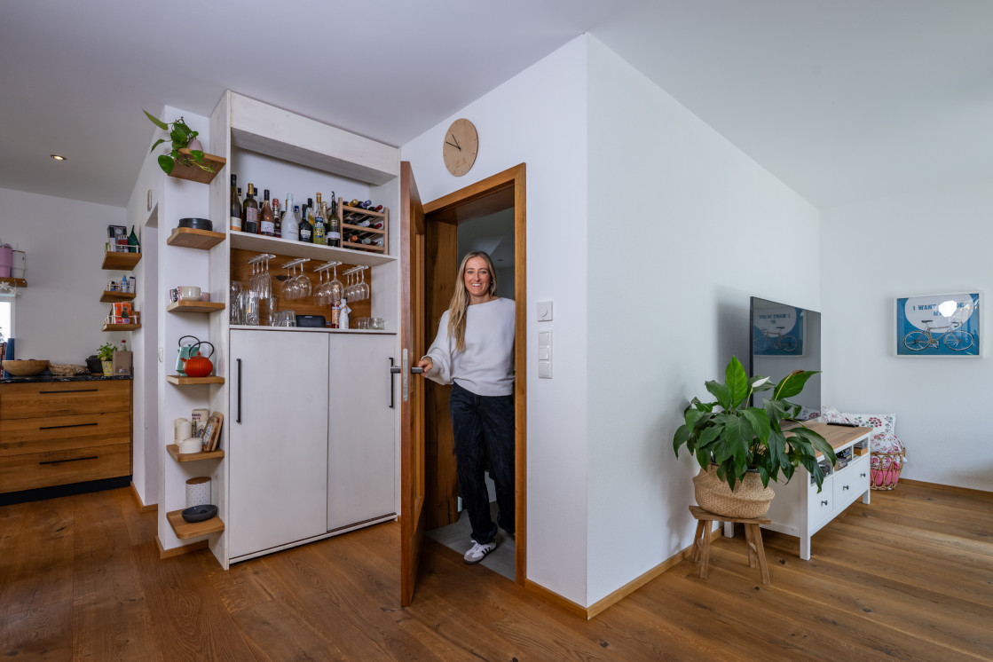 Bewohnerin im Wohnbereich mit JOKA Holzboden und maßgefertigten Holzmöbeln.