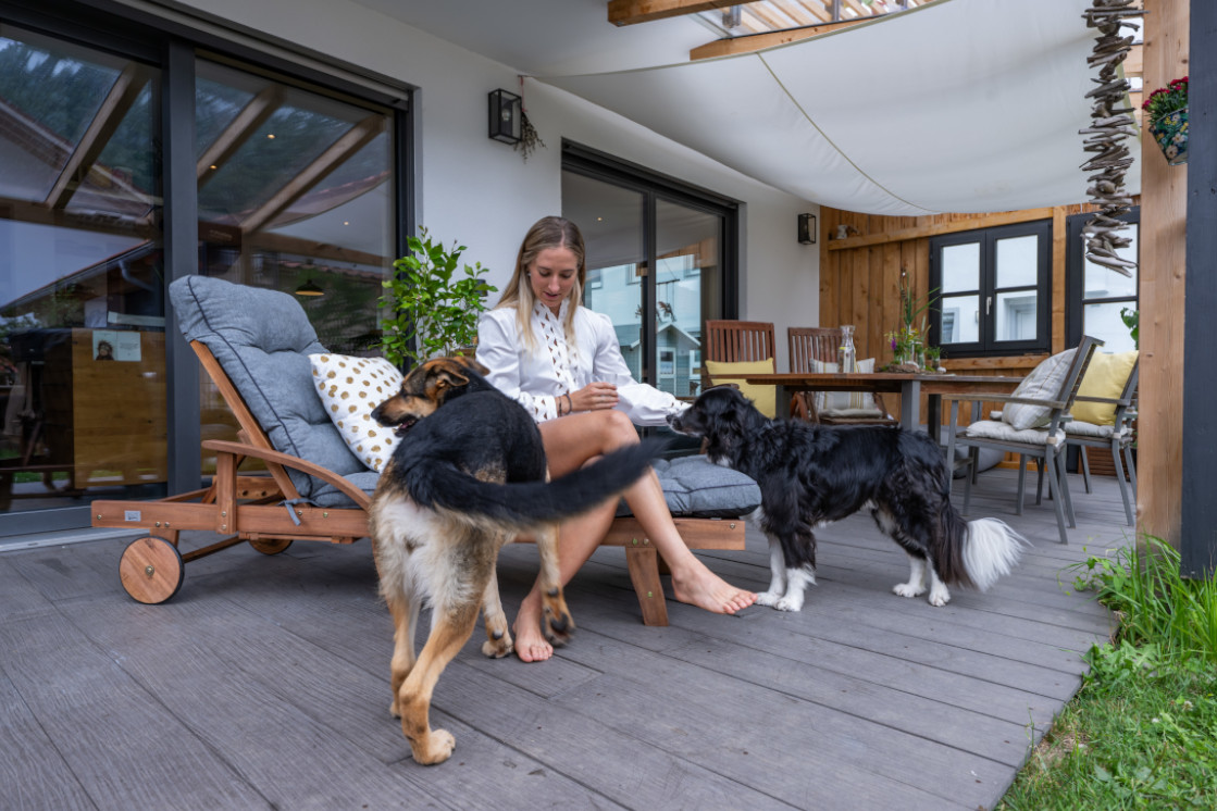 Terrasse mit Holzdielen und Blick in den Wohnbereich, harmonischer Übergang zwischen Innen und Außen.