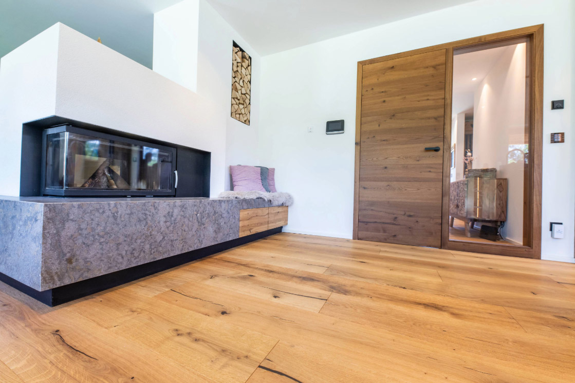 Ein moderner Wohnbereich mit einem hellen Parkettboden, der in ein Wohnzimmer mit einem Kamin und einer weißen Wandgestaltung übergeht.