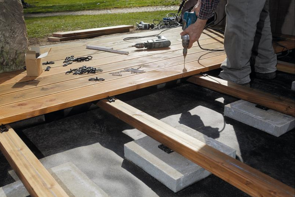 Bild das den Aufbau einer Terrasse zeigt mit der Verlegung und Befestigung der Terrassendielen.