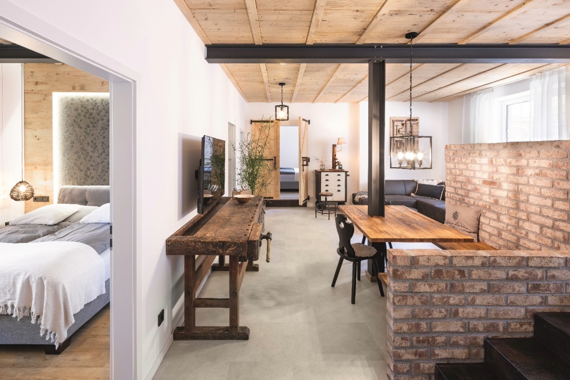 Das Bild zeigt ein stilvolles Apartment mit offenem Grundriss, in dem JOKA Designboden und JOKA Holzpaneele eine warme, moderne Wohnatmosphäre schaffen.