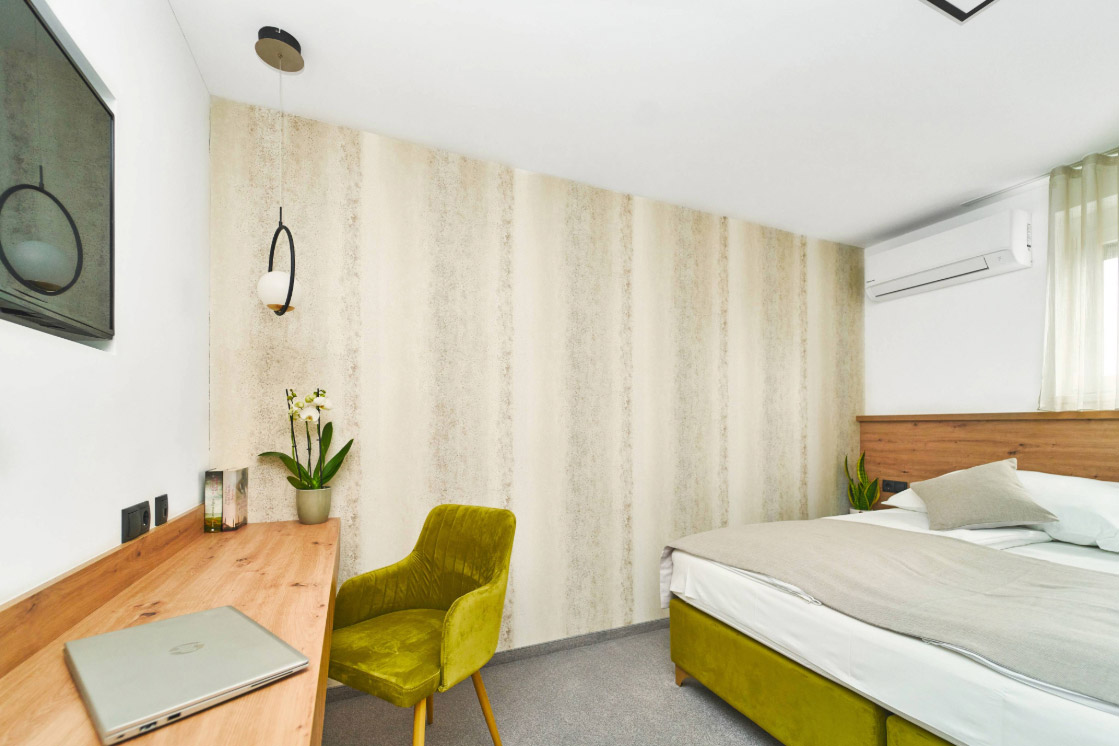 JOKA-Referenzen-Tapete-Hotelzimmer Raumbild eines hellen Hotelzimmers, in dem die beige gemusterte JOKA Atmosphere Tapete angebracht ist.