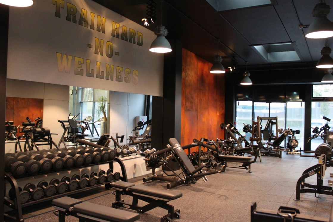 Fitnessstudio mit Hanteln und Geräten.