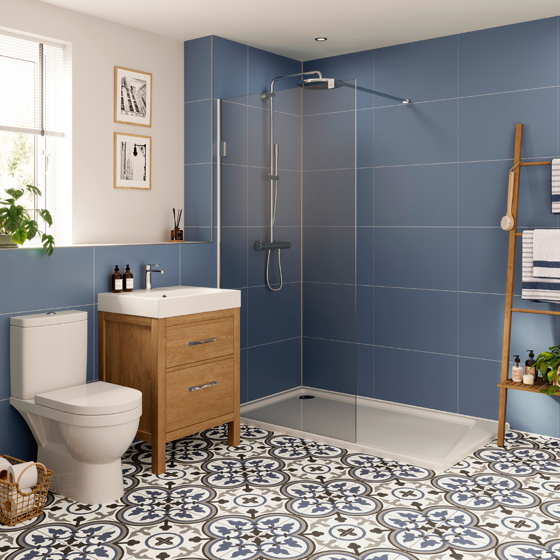 Freundlich gestaltetes Bad mit blauer Wandverkleidung, bodengleicher Dusche und Holzdetails – frisches SpaSense-Ambiente von JOKA.