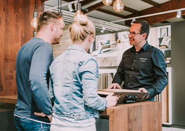 Ein JOKA Showroom Berater berät ein junges Paar bei der Auswahl der richtigen Böden für ihr Zuhause.