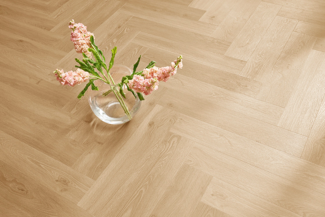 Detailaufnahme eines hellen Holzbodens aus der JOKA Kollektion 555 mit Glasvase und Blumen.