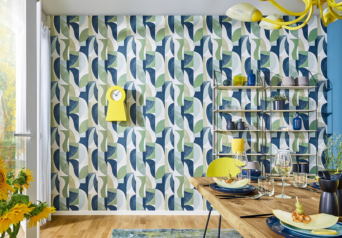 Detailaufnahme einer blau, grün, gelb gemusterten JOKA Tapete. Der Blickfang für die Raumgestaltung in der Lebensfreude Wohnidee.