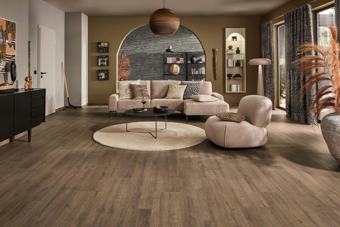 Großzügiges Wohnzimmer mit JOKA Laminatboden in Holzoptik und rundem Teppich.