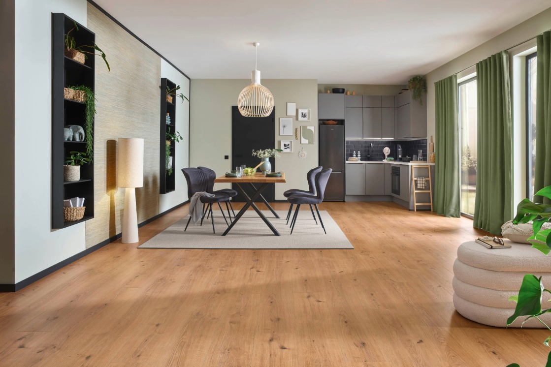 Raumbild einer Küche, gestaltet mit JOKA Laminatboden Skyline, einem großen JOKA Esstisch und einem abgepassten Teppich. Alles im Stil Wohngenuss